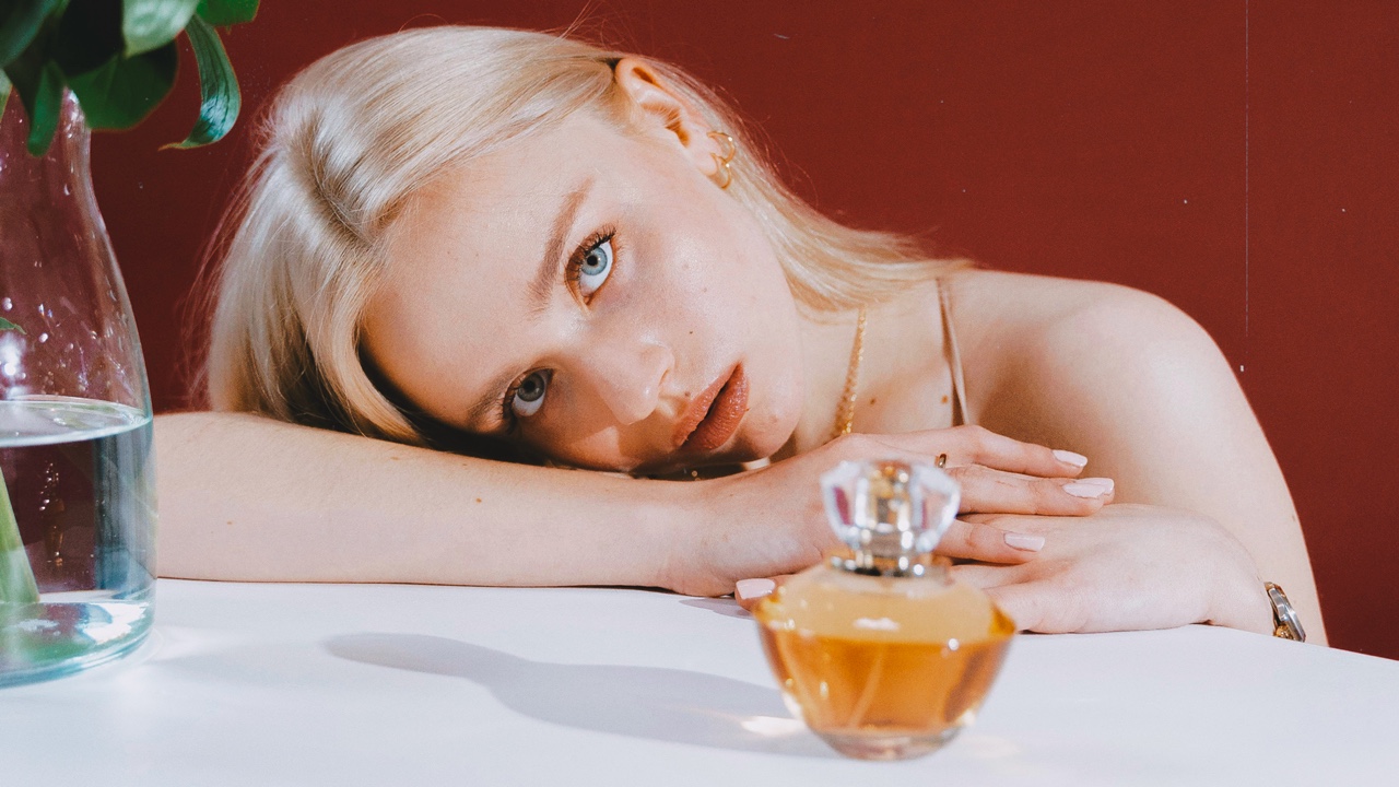 Woman posing next to Perfume bottle