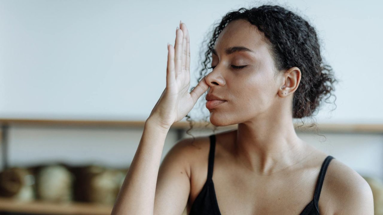 Close-up of a woman practicing yoga breathing techniques indoors, focusing on relaxation.