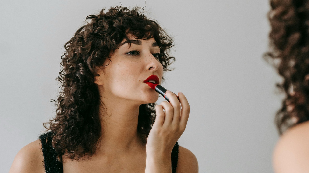 Woman Applying lipstick in mirror
